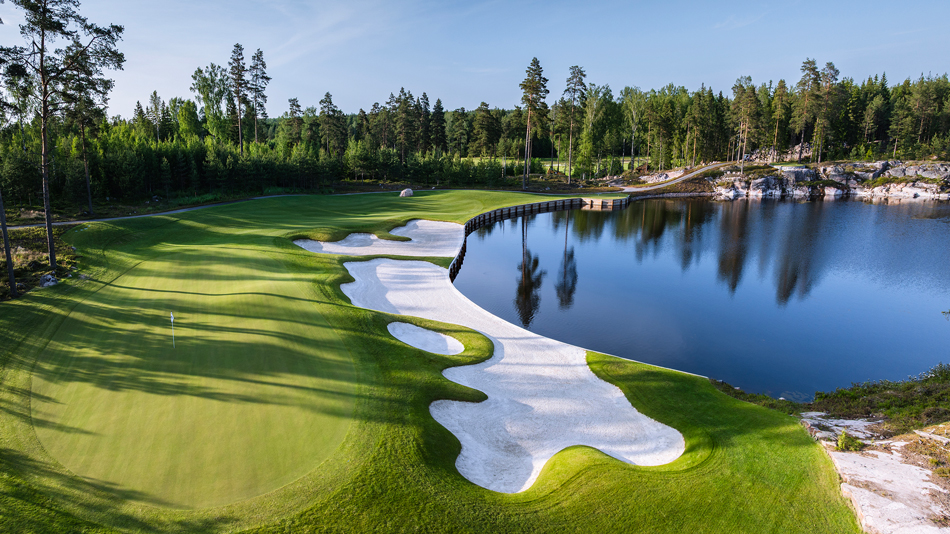 The Rock golf course — a sweeping green and white bunkers beside a still lake ringed by Finnish pine forest