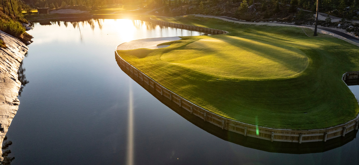 The Rock golf course outside Helsinki — granite boulders beside a misty fairway lined with pines at golden hour